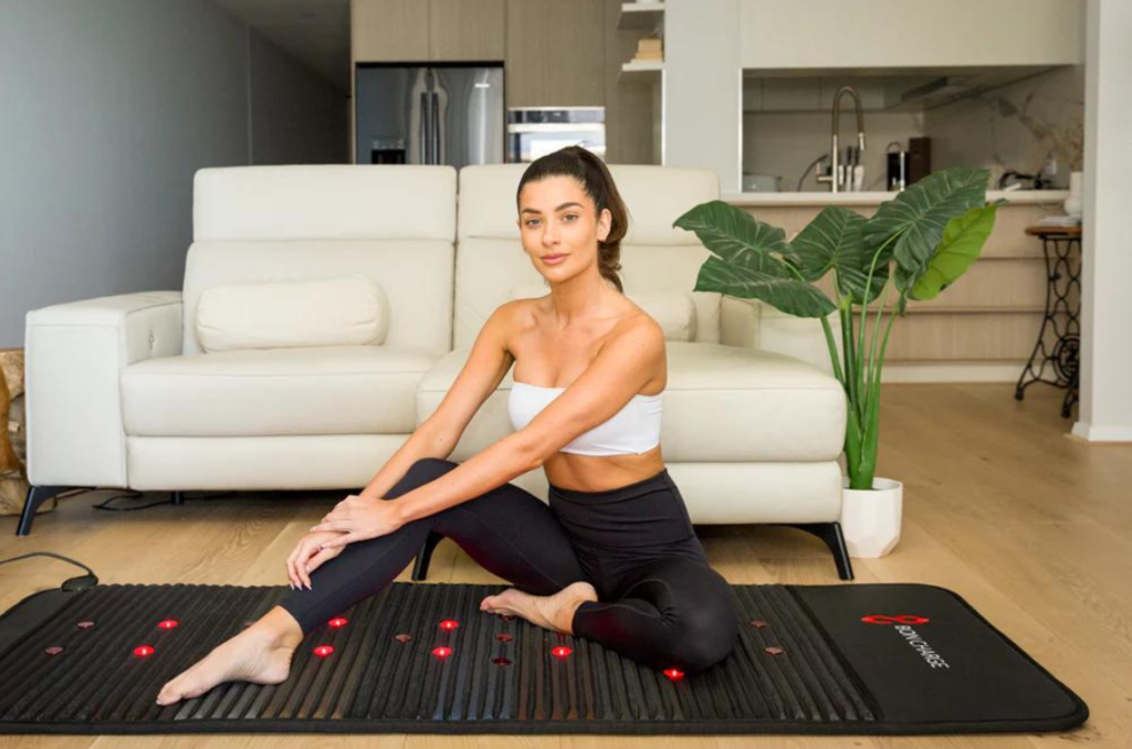 Woman sitting on PEMF therapy mat.